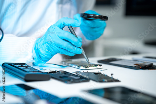 Technician in blue gloves repairs an opened smartphone with precision tools at a clean electronics workbench, highlighting mobile service, technology, and device maintenance.