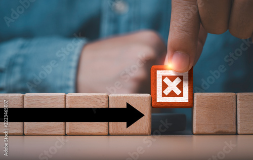 Business risk management and problem solving concept with a hand removing a wooden block marked X from an arrow path symbolizing obstacle removal, strategic decisions and business continuity.