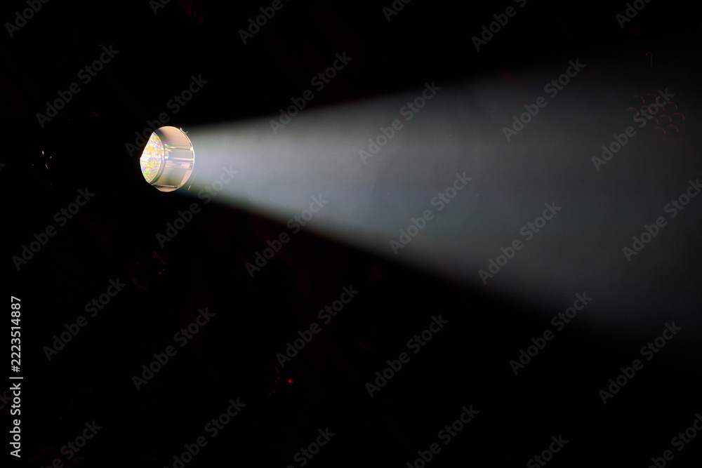 Fototapeta premium Stage spotlight casting a bright beam of light in a dark venue in Rybnik, Poland