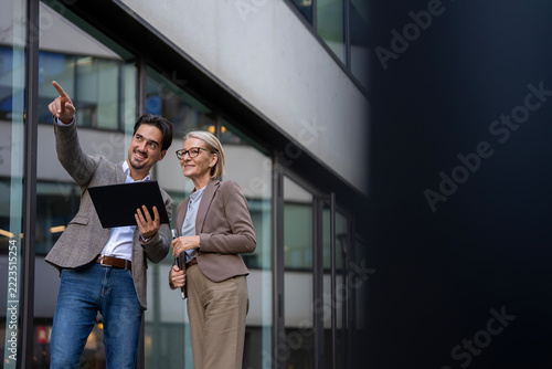 Business colleagues discussing future plans pointing building exterior