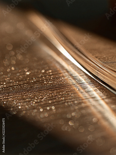 Macro shot of soft golden light reflecting on a wooden desk and notebook