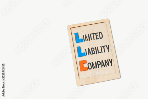 Limited liability company concept on wooden board over white background.