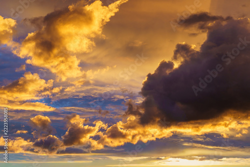 Dramatic clouds in the sky as the sun sets, as the whole sky is lit up with yellow and orange glow. 