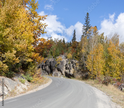 Road in northern Ontario with beautiful fall colors in forest along the rock wall