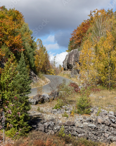 Road in northern Ontario with beautiful fall colors in mixed boreal forest atop jagged rock walls 