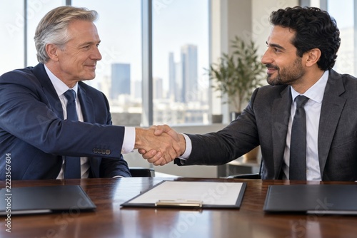 Businessmen shaking hands across a table after a successful agreement