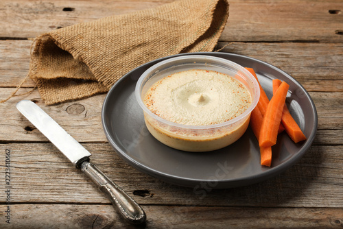 Hummus Served With Fresh Carrot Sticks on a Wooden Table