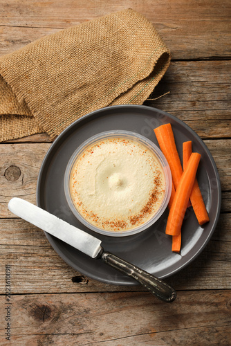 Hummus Served With Fresh Carrot Sticks on a Wooden Table