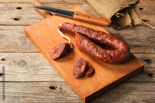 Spanish Chorizo Rests on a Wooden Board With Knife and Slices Nearby