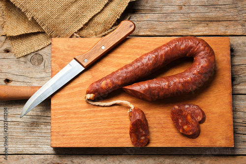 Spanish Chorizo Rests on a Wooden Board With Knife and Slices Nearby