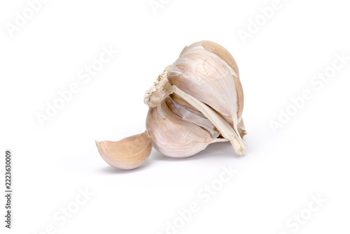 Garlic bulb leaning with one clove on white
