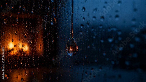 Moody rainfall on window with warm glow: capturing tranquil night ambiance