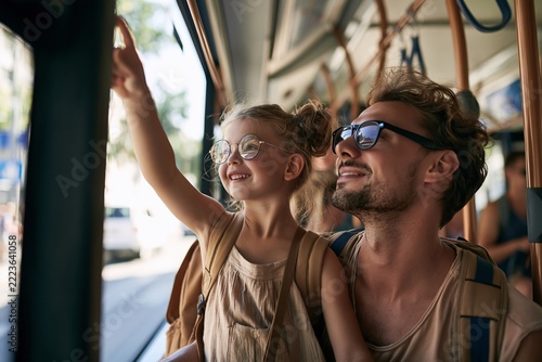 Happy father and daughter traveling together by public transport and looking out the window