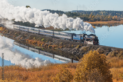 Retro steam train moves along the lake.
