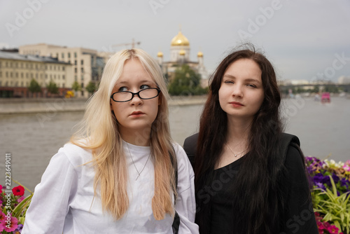 Two young women standing outdoors near river in european city with golden dome cathedral in background. Urban tourism and friendship concept for vacation and sightseeing travel exploration