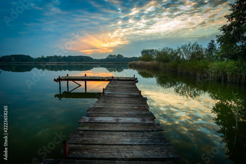 Lake landscape with a wooden pier at sunset.