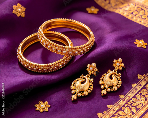 Traditional Indian Gold Bangles and Peacock Earrings Set on Purple Silk Fabric Background