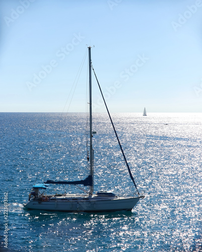Elegant monohull sailing yacht with a single tall mast and a blue mainsail cover cruising on the calm waters of the Mediterranean Sea.