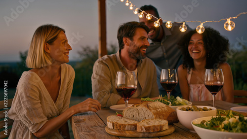 Cozy outdoor summer dinner party with friends and red wine