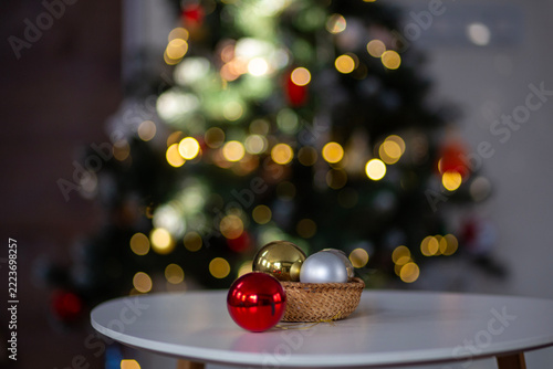 Christmas ornaments in basket with decorated tree and bokeh lights. Christmas ornaments, decorated Christmas tree with warm bokeh lights