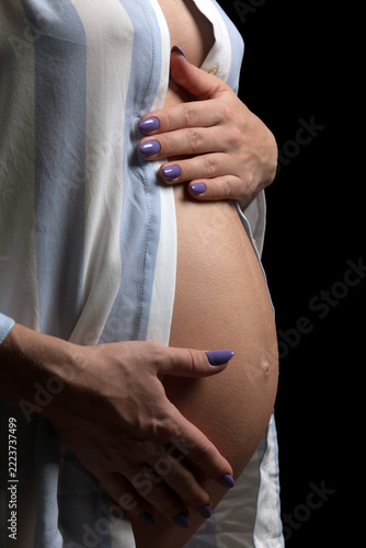 pregnant woman touching her belly, black background