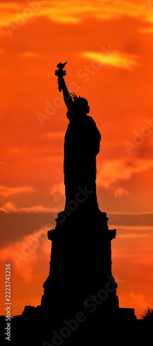 Statue of Liberty in New York, USA, in silhouette against a fiery red and orange sunset sky