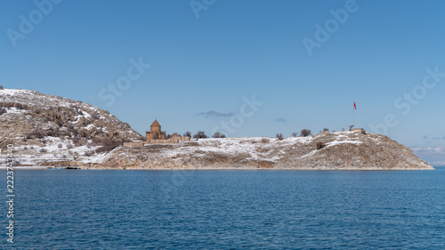 Akdamar Island in Lake Van, Turkey, in winter, with the Armenian Church of the Holy Cross on its snowy shore and a Turkish flag on the hilltop