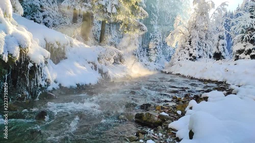 Seamless 4k looping video (1 min) of a steaming winter river flowing through a magical snowy forest at sunrise. natural sound of the river