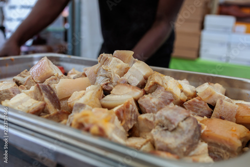 Cooked meat pieces in a metal tray at a food counter