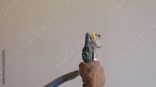 Worker applying plaster to interior wall using mechanical spray gun