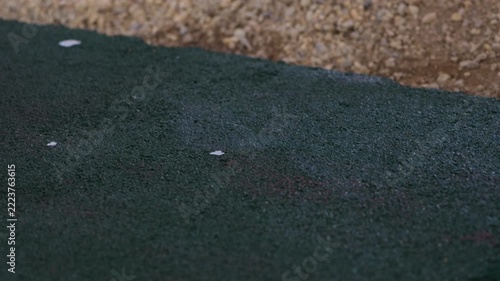 Worker applying adhesive to rubber crumb flooring with paint roller