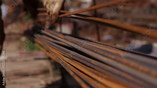 Construction worker stacking steel reinforcement bars at building site
