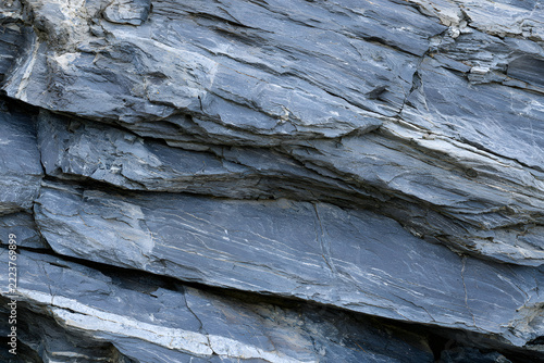 A textural rock gray-blue eroded surface; natural stone surface with rough texture featuring layered details; conveys geological resilience and raw environment.