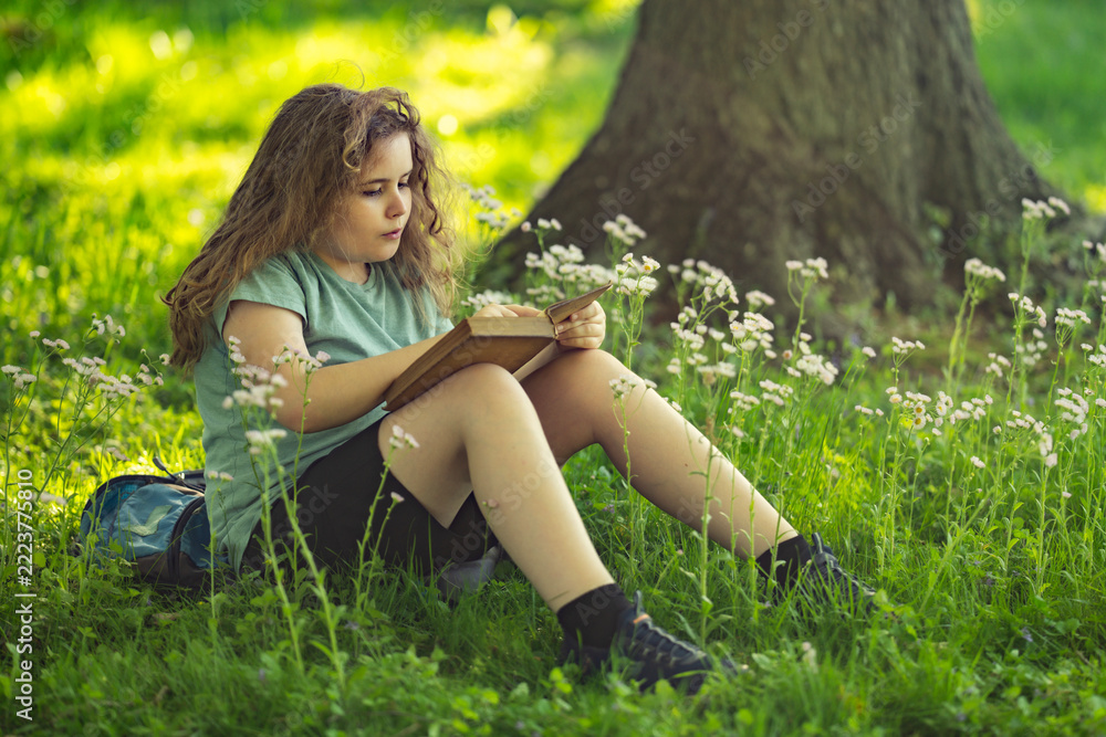 Fototapeta premium Smart kid studies storybook outdoors. Focused smart reader builds knowledge. Smart childhood connects education and nature. Smart learning feels creative and calm.