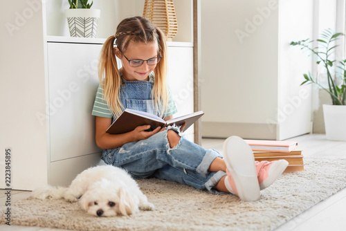 Education and childhood development, young girl reading a book at home with h...