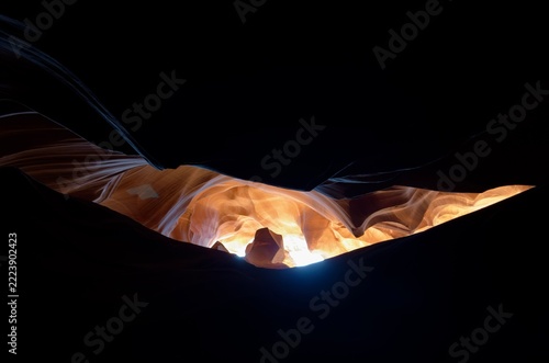 Dark sandstone silhouette with glowing light at the bottom of the slot in Antelope Canyon, Arizona