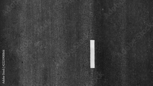 High-angle aerial image of a dark asphalt roadway with lane markings, highlighting travel, progress, connectivity, infrastructure planning, movement, simplicity, and urban development concepts. 4k.
