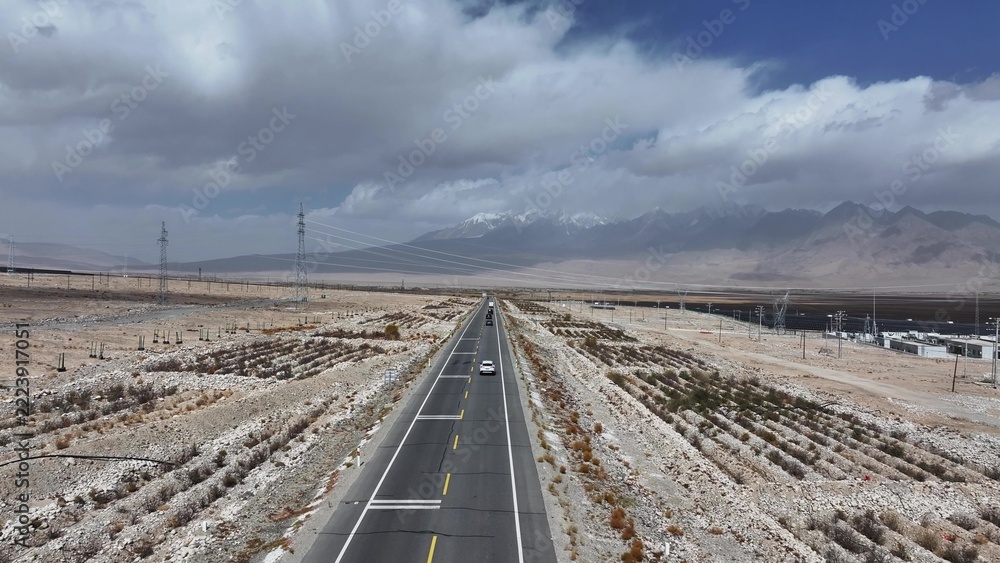 Fototapeta premium Highway crossing gobi desert leading to snow mountains in xinjiang