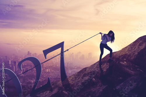 Businesswoman Pulling Giant 2027 Year Numbers Up a Mountain Peak