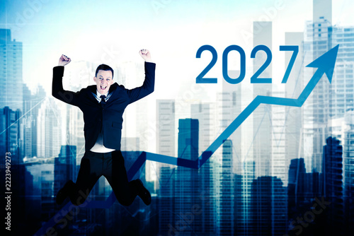 Excited Businessman Jumping with 2027 Growth Chart Over City Skyline