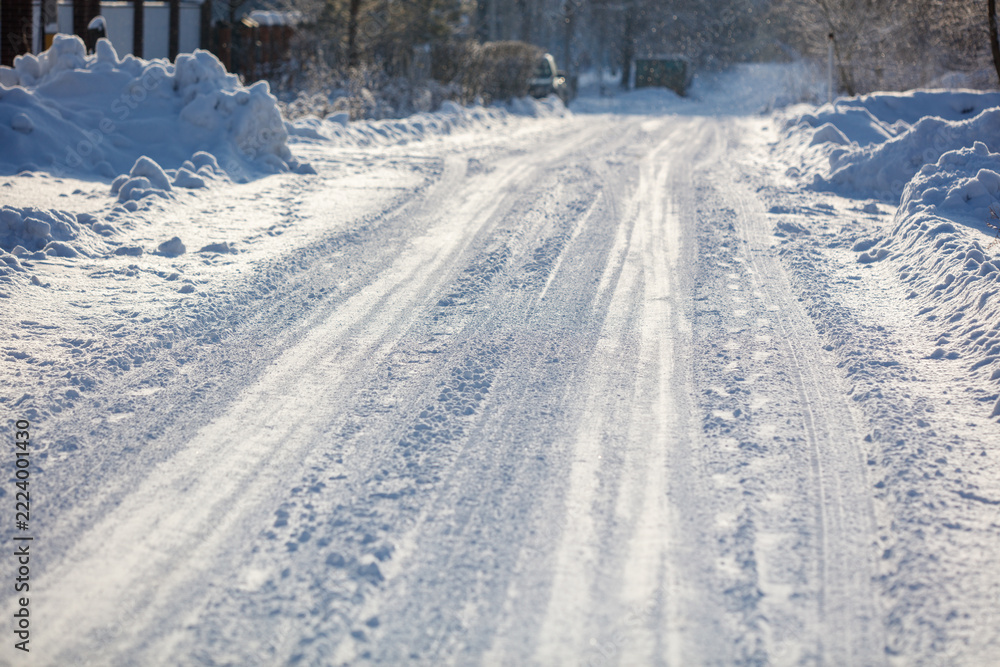 Fototapeta premium Snow covers a quiet road with tire tracks