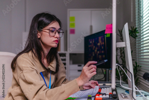Female data scientist analysing machine learning results on computer screen in office at night