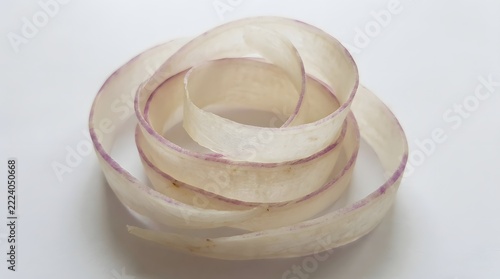 A beautifully rolled and carefully layered silk scarf in shades of beige and white is displayed on a pristine white surface highlighting its refined texture