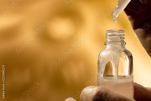 Hands Holding Serum Dropper and Amber Bottle with Copy Space