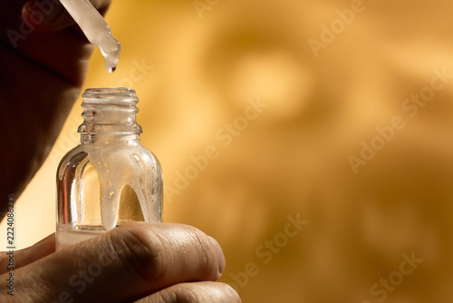 Hands Holding Serum Dropper and Amber Bottle with Copy Space