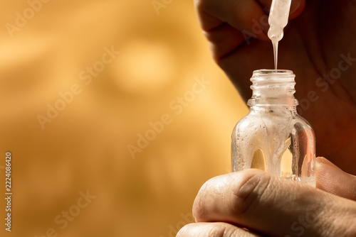 Hands Holding Serum Dropper and Amber Bottle with Copy Space