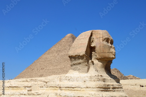 great sphinx of giza egypt. A close-up profile view of the Great Sphinx of Giza with the Great Pyramid rising prominently behind it. The weathered limestone face of the Sphinx is in sharp detail.
