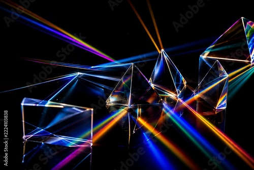 Glass prisms refracting colorful light beams against a dark background with artistic reflections