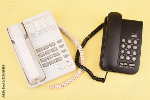 Retro black and white telephones on a yellow background. Top view. Concept of vintage technology, traditional telecommunication and minimalism.