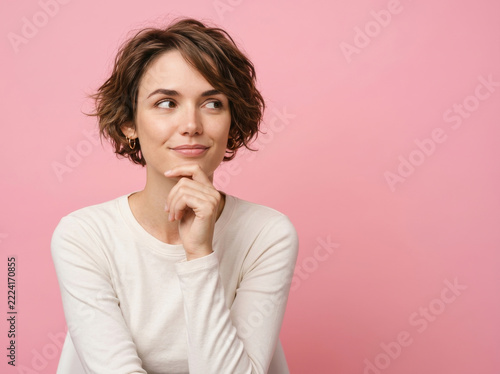 Thoughtful woman with short hair posing on pink background